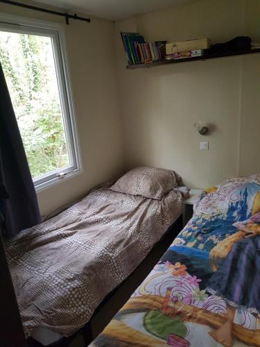 une chambre avec deux lits et une fenêtre dans l'établissement Mobilhome 6 places dans camping 4* Finistère Sud, à Saint-Yvy