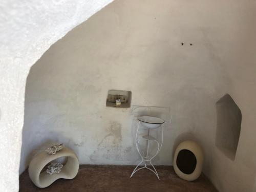 een kamer met een witte muur met een kleine doos en een kruk bij Trullo Mareposa in Sannicola