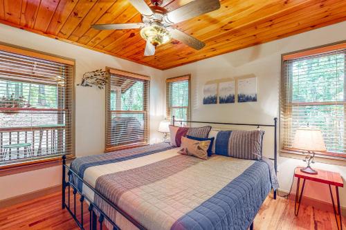 a bedroom with a bed with a ceiling fan and windows at Roosters Roost in Blue Ridge