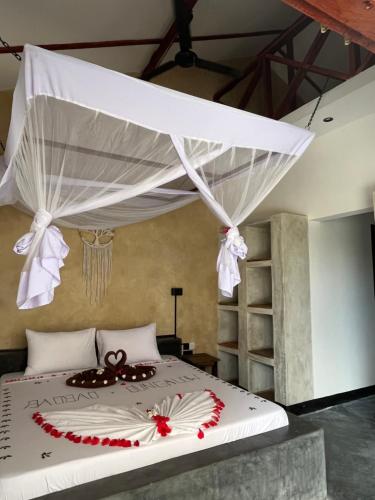 a bedroom with a white bed with a canopy at Baobab Bungalows in Jambiani