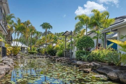 a koi pond in a garden with palm trees at Tranquil Noosa retreat minutes from the river 40IP in Noosaville