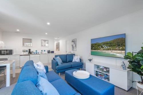 a living room with a blue couch and a tv at Tranquil Noosa retreat minutes from the river 40IP in Noosaville
