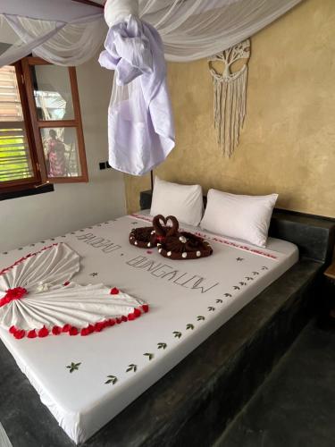a bed in a room with a white bedspread with a bow at Baobab Bungalows in Jambiani