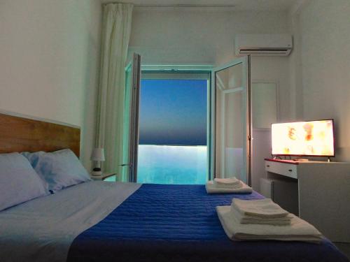 una camera da letto con un letto con una coperta blu e una finestra di Albergo Lido Diomedee a Rodi Garganico