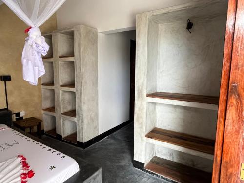 a room with a bed and a book shelf at Baobab Bungalows in Jambiani
