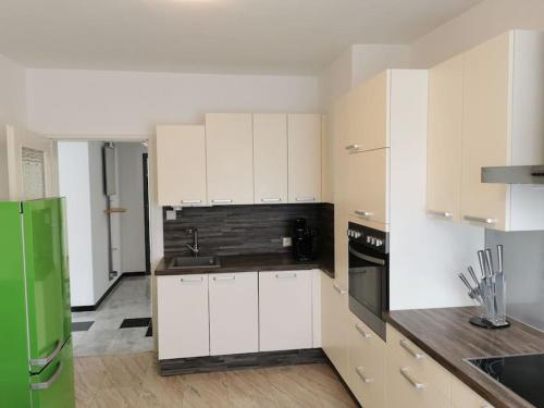 uma cozinha com armários brancos e um frigorífico verde em Großzügige Wohnung mit Terrasse em Zeltweg