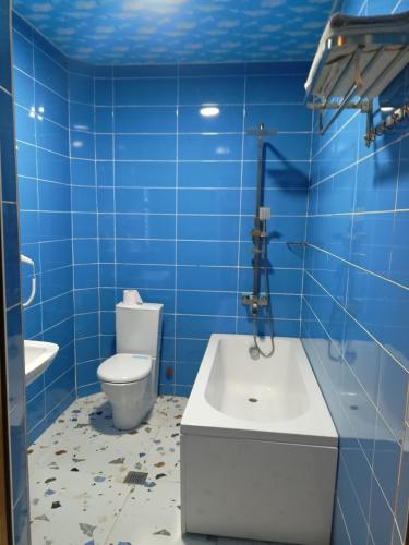 a blue tiled bathroom with a toilet and a sink at Hotel Lilo near Airport in Tbilisi City