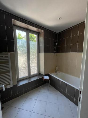 une salle de bain avec une baignoire et une fenêtre dans l'établissement maison lumineuse, à Villemoustaussou