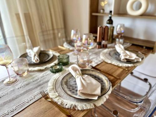 a wooden table with plates and napkins and wine glasses at BALI HOME Stylische Wohnung mit Terrasse in Schönefeld