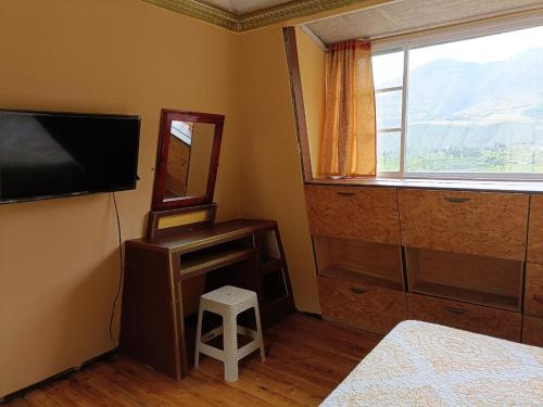 1 dormitorio con TV, espejo y taburete en BUNGALOWS YAHUARCOCHA en Ibarra