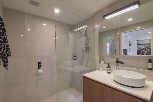 La salle de bains est pourvue d'un lavabo et d'une douche en verre. dans l'établissement Luxury in the Heart of Hastings street 628, à Noosa Heads