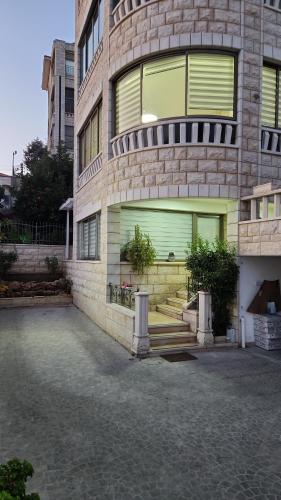 een groot bakstenen gebouw met groene deuren en trappen bij Maria's GuestHouse - Uphill View of Nazareth F in Nazareth