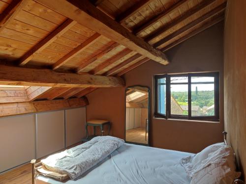 - une chambre avec un lit doté de plafonds en bois et d'une fenêtre dans l'établissement Mas avec piscine, à La Bastide-dʼEngras