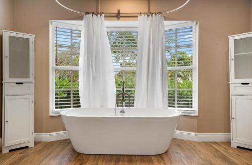 a bath tub in a bathroom with two windows at Ultimate Waterfront Oasis Heated Pool & Boat Dock in Tampa