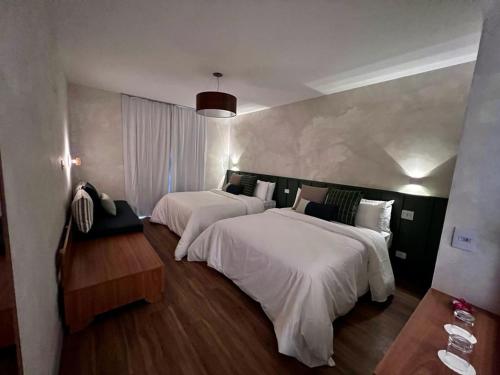 a hotel room with two beds with white sheets at Hotel Fazenda Brisa Itu in Itu