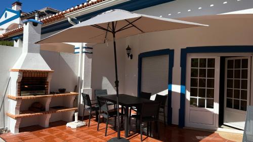 a patio with a table and an umbrella at Casa da Praia - Golf Resort Praia D'El Rey in Amoreira