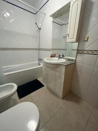 a white bathroom with a toilet and a sink at Rosas no Lagar in Vila Nova De Cacela