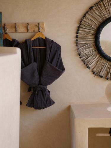 a robe hanging on a wall next to a mirror at Berber Beldi Camp in Imsouane