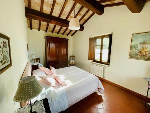 Un dormitorio con una cama con sábanas blancas y almohadas rosas. en Frateria Di San Benedetto, en Montepulciano