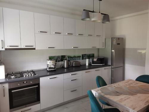 a kitchen with white cabinets and a wooden table with a tableablish at Apartmant Melinda M26 in Braşov