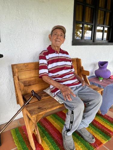 an older man sitting on a wooden bench at HOTEL CAMPESTRE ABRAZO DEL ANGEL in Aratoca