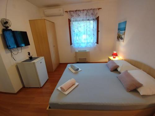 a bedroom with a large bed with two towels on it at Soba Ivanka Nikšić in Karlobag