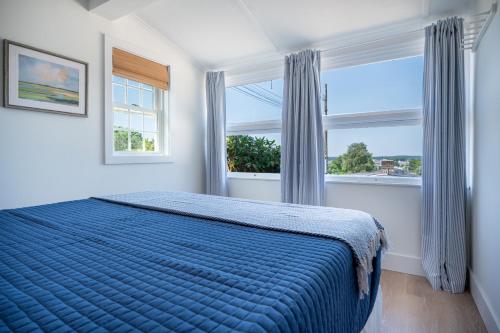 a bedroom with a blue bed and two windows at Marina Bay Cottages in Waterford