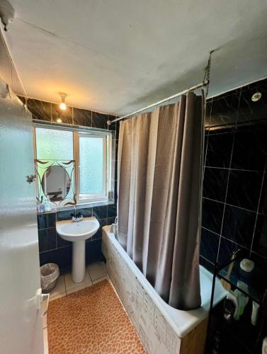 łazienka z zasłoną prysznicową i umywalką w obiekcie Whitechapel Rooms R3 w Londynie