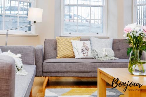 ein Wohnzimmer mit einem grauen Sofa und einem gelben Kissen in der Unterkunft Montmartre Suite - New Town 3BR-3BA Main Door - Free Parking & Patio by Bonjour Residences Edinburgh in Edinburgh