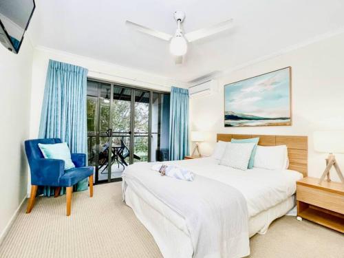 a bedroom with a large bed and a blue chair at Poolside Retreat at Tropical Resort 126IP in Noosaville