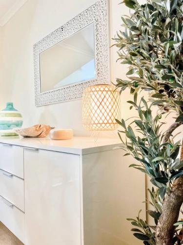a white dressing table with a mirror and a plant at Poolside Retreat at Tropical Resort 126IP in Noosaville