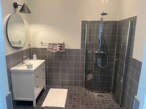 a bathroom with a shower and a sink and a mirror at Skolan i Näsby lägenhet D in Lövestad