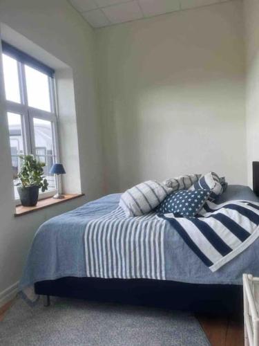 a bedroom with a bed with blue and white sheets and a window at Skolan i Näsby lägenhet D in Lövestad