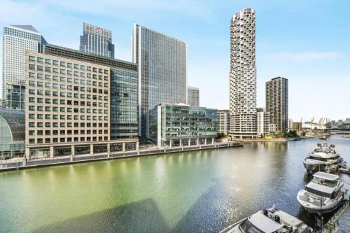 a river with boats in a city with tall buildings at Spacious Two Bedroom Apartment in London