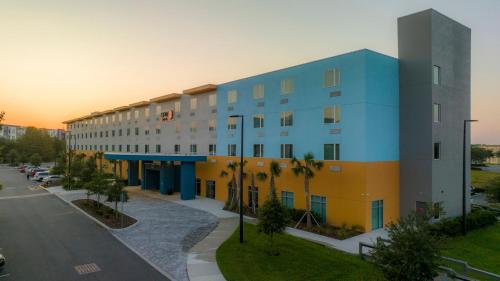a building on a street with palm trees in front of it at SPOT X Hotel Orlando Intl Dr by The Red Collection in Orlando