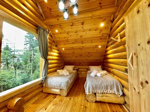 two beds in a log cabin with a window at Cottage farvana in Khulo