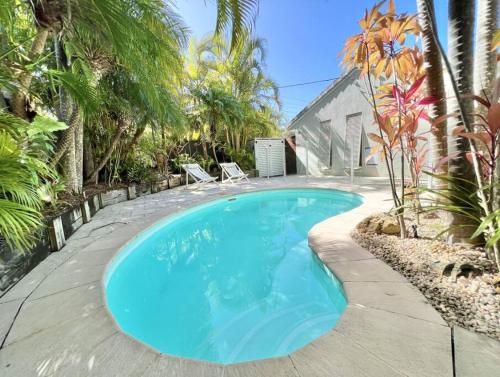 a swimming pool in a backyard with palm trees and a house at Sunshine Beach Oasis Private Pool Pet Friendly solway in Sunshine Beach