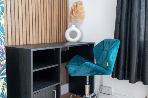 a desk with a blue chair and a vase at Exclusive Deals l Last-Minute Reserve l Townhouse with Sleeps 6 l Braunstone Town , Leicester l By Zen Nights Short Lets & Serviced Accommodations in Braunstone