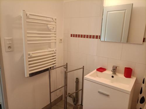 ein weißes Badezimmer mit einem Waschbecken und einem Spiegel in der Unterkunft Le Petit Nid de Nant in Nant