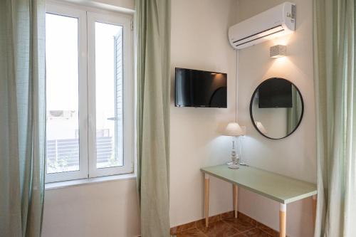 Habitación con espejo, mesa y ventana en Sunny yard apartments, en Poros