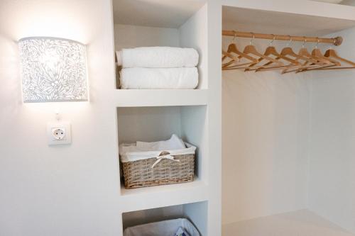 a bathroom with a closet with towels and a shelf at Sunny yard apartments in Poros