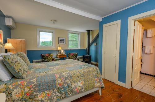 a bedroom with a bed and blue walls at Brass Lantern Inn in Stowe