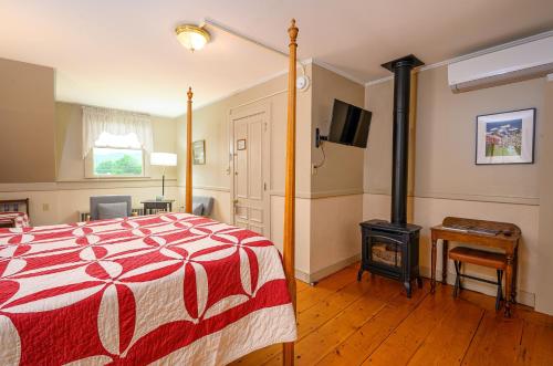 a bedroom with a bed and a wood stove at Brass Lantern Inn in Stowe