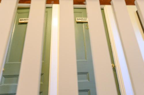a group of three green doors with signs on them at Brass Lantern Inn in Stowe