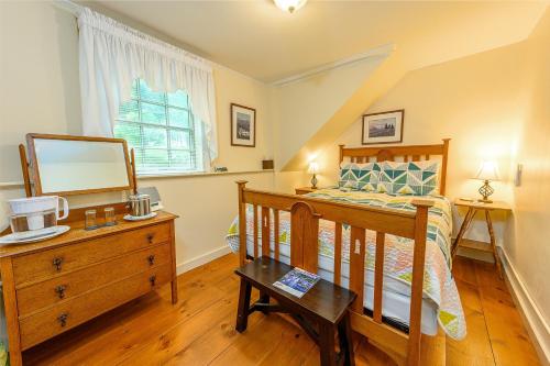 a bedroom with a bed and a dresser and a mirror at Brass Lantern Inn in Stowe