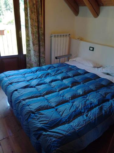 uma grande cama azul num quarto com uma janela em Casa Prucci em Battigio