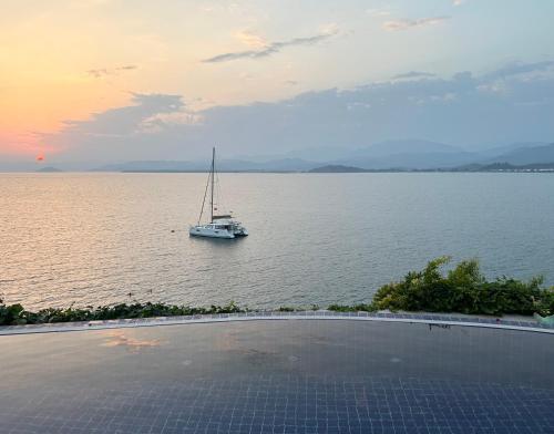 a sailboat on the water with a boat in the ocean at Ece Hotel Sovalye Island in Fethiye