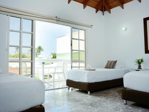 a white bedroom with two beds and a large window at Hotel Koray in San Andrés