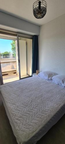 une chambre avec un grand lit blanc avec une fenêtre dans l'établissement F2 confortable Carnon-Plage, à Carnon-Plage