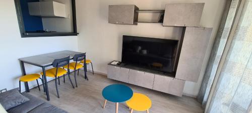 sala de estar con TV, mesa y sillas en F2 confortable Carnon-Plage, en Carnon-Plage